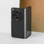 A black foldable smartphone showcased against a brown and white background, highlighting its modern design.