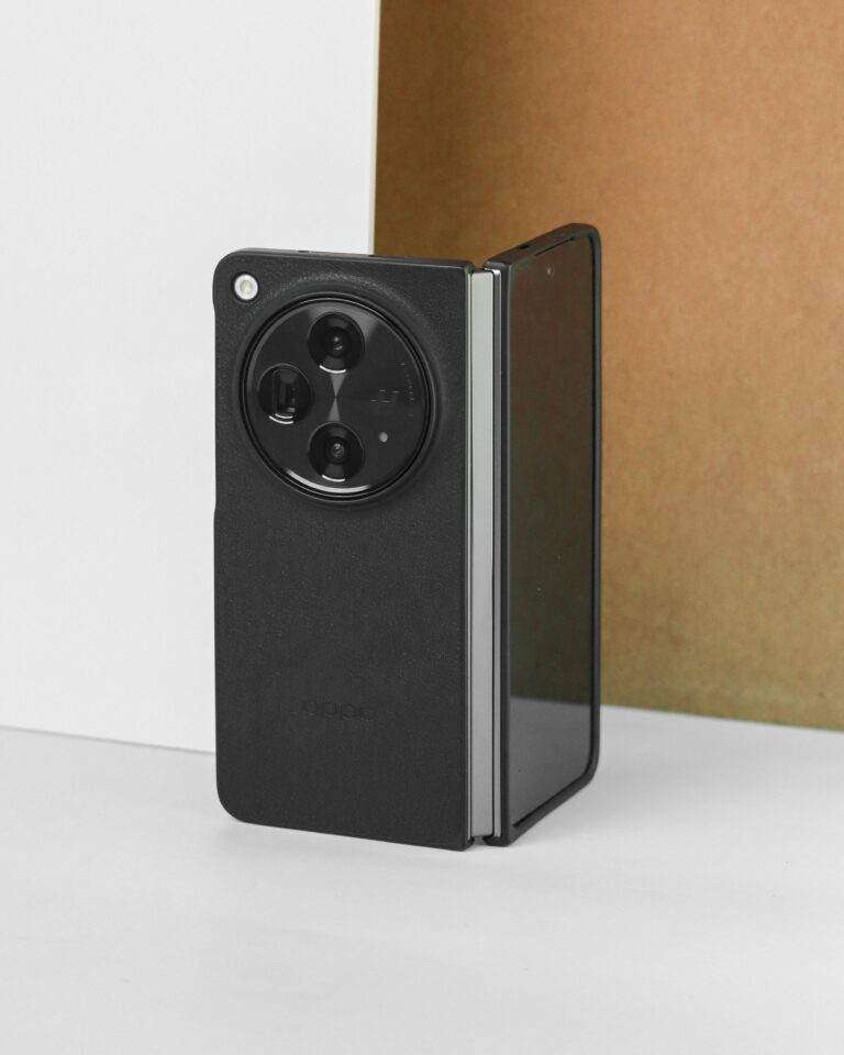 A black foldable smartphone showcased against a brown and white background, highlighting its modern design.