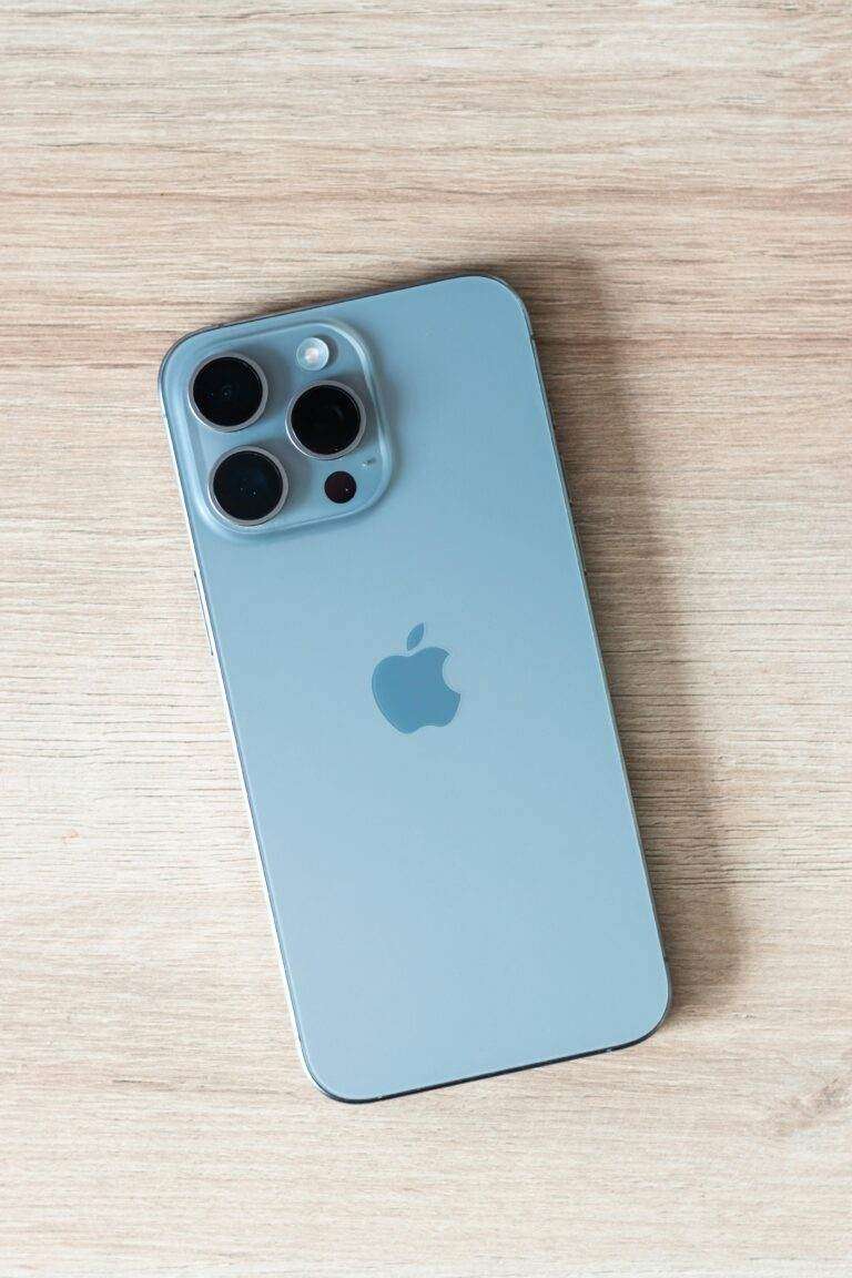 Close-up of a modern smartphone on a light wooden table surface.