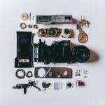 Flat lay of various disassembled camera parts on a white surface showcasing intricate details.
