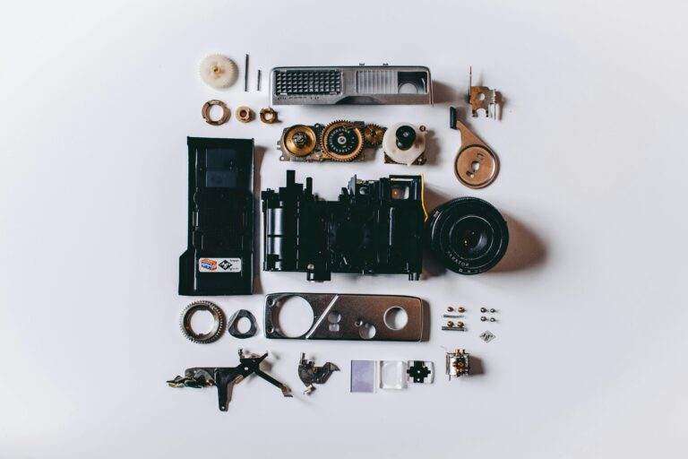 Flat lay of various disassembled camera parts on a white surface showcasing intricate details.