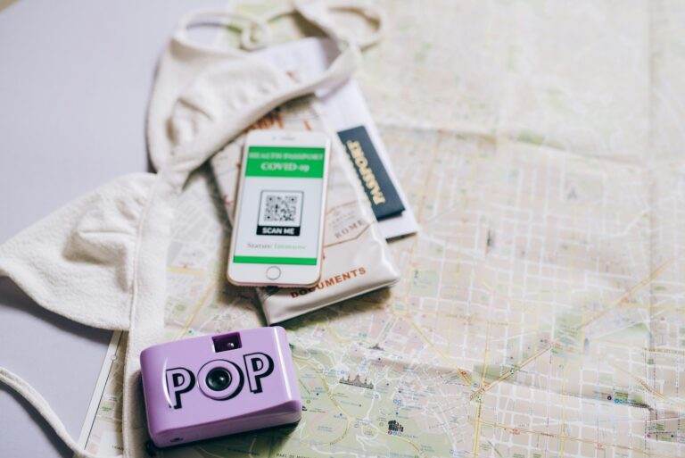 Scanner un code QR sur smartphone : la manipulation que tout le monde croit maîtriser Flat lay of travel essentials including a passport, map, smartphone, and pop camera.