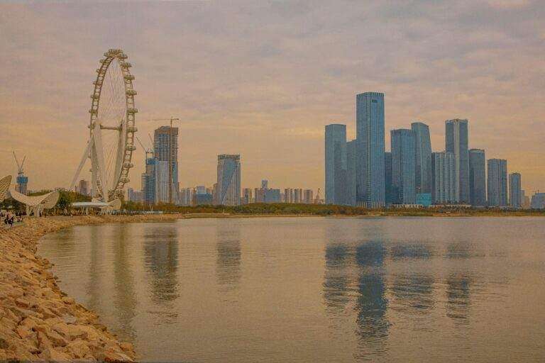 Captivating view of Shenzhen skyline and Ferris wheel reflected in the water during twilight.