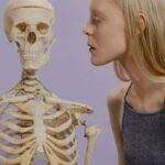 An artistic portrayal of a woman and skeleton against a purple background.