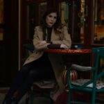 Woman sitting in a cozy cafe with warm lighting, creating a relaxed ambiance.