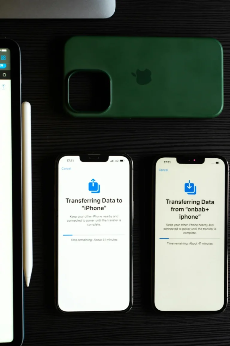 Two smartphones transferring data, showcasing modern mobile technology on a dark desk.