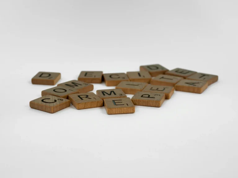 Close-up of wooden Scrabble tiles on a white surface, ideal for creative concepts.