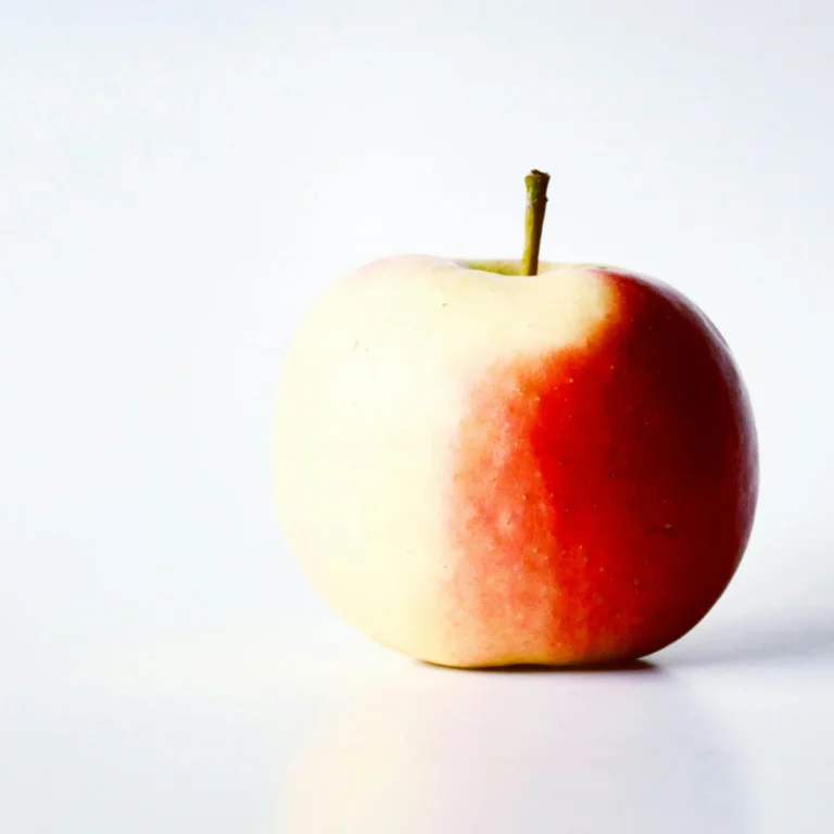 Close-up of a vibrant red apple with a stem, isolated on a white background.