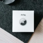 Overhead image of Apple Airtag packaging on a textured surface, showcasing product simplicity.