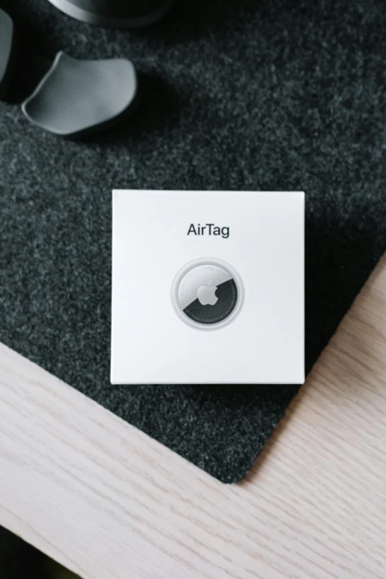 Le pack de 4 Apple AirTags à seulement 64 $ sur Amazon — économisez 35 $ dès maintenant Vertical shot of an Apple AirTag leather key ring box placed on a wooden table surface.