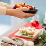 Caterer arranging fresh fruits and snacks on a table for a food service event.
