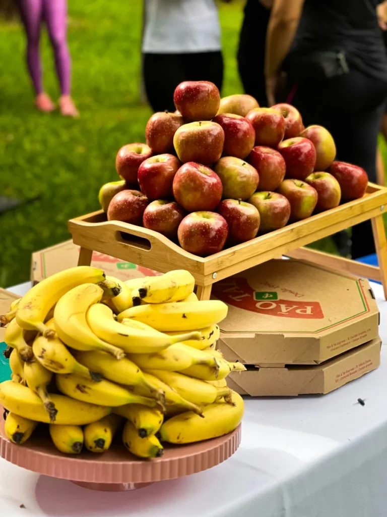 Vibrant display of apples and bananas at an outdoor market with people in the background.