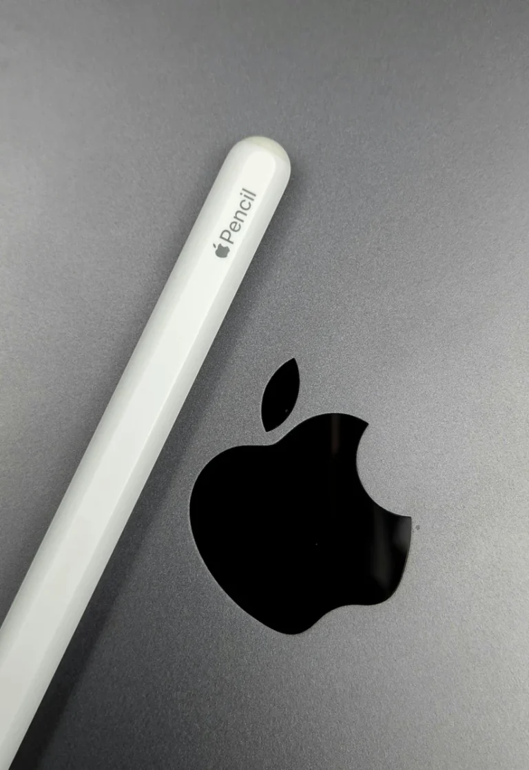 Minimalist shot of an Apple Pencil lying on a MacBook, showcasing sleek design.