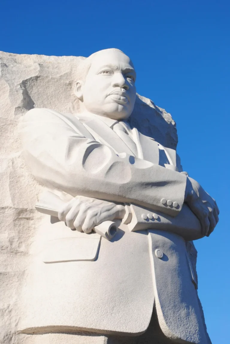 Stone statue of Martin Luther King Jr. against a clear blue sky at the Washington DC memorial.