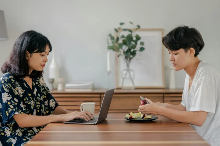 Apple mise gros comme Netflix : ce que le partenariat autour de ‘Severance’ révèle de sa nouvelle stratégie Two people sitting indoors, working and preparing food in a cozy home setting.