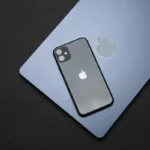 Modern workspace showcasing Apple laptop, tablet, and smartphone on a wooden desk.