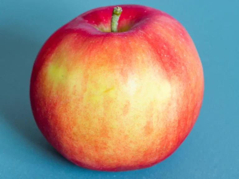 Vibrant red apple against a blue backdrop, perfect for healthy eating themes.