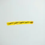 A strip of yellow danger tape against a plain gray wall, conveying caution.