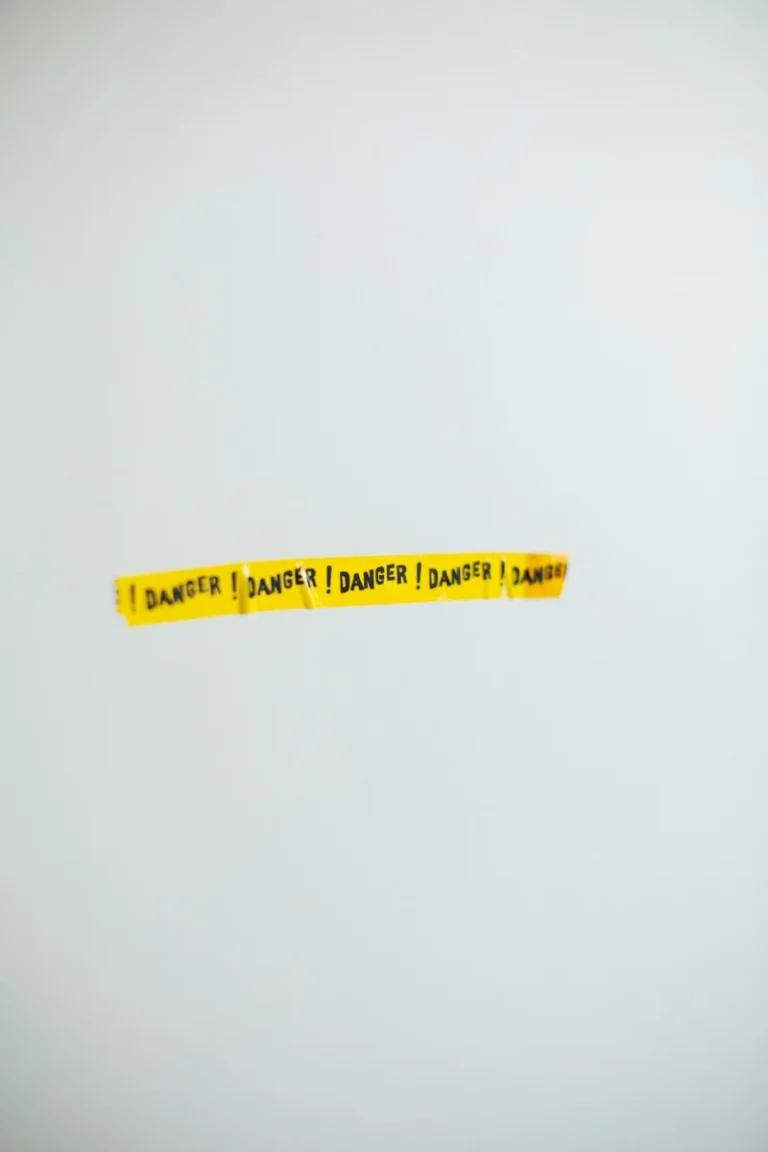 Apple lance un avertissement décisif qui pourrait transformer le cycle des iPhone 2026 A strip of yellow danger tape against a plain gray wall, conveying caution.