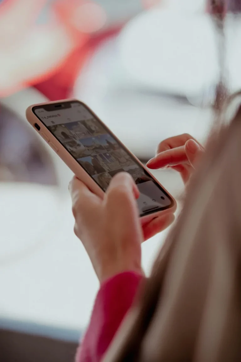 Hands holding a smartphone, browsing social media outdoors on a sunny day.