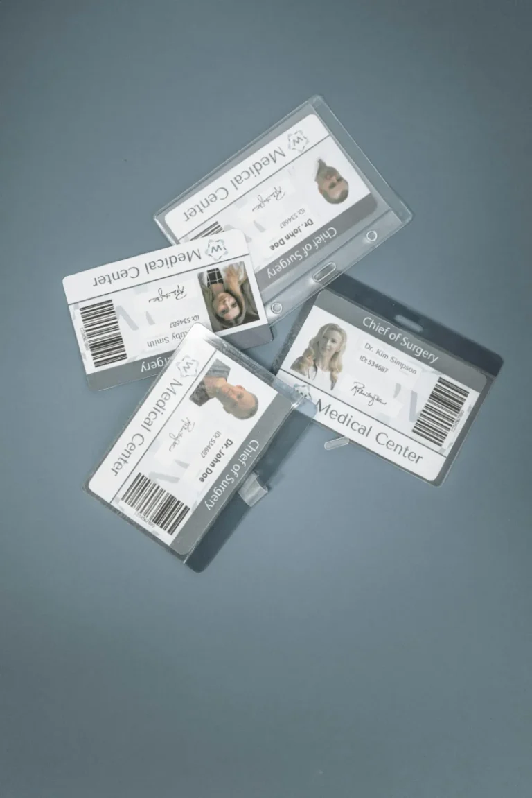 Four medical ID badges of doctors arranged on a blue surface, showcasing healthcare roles.