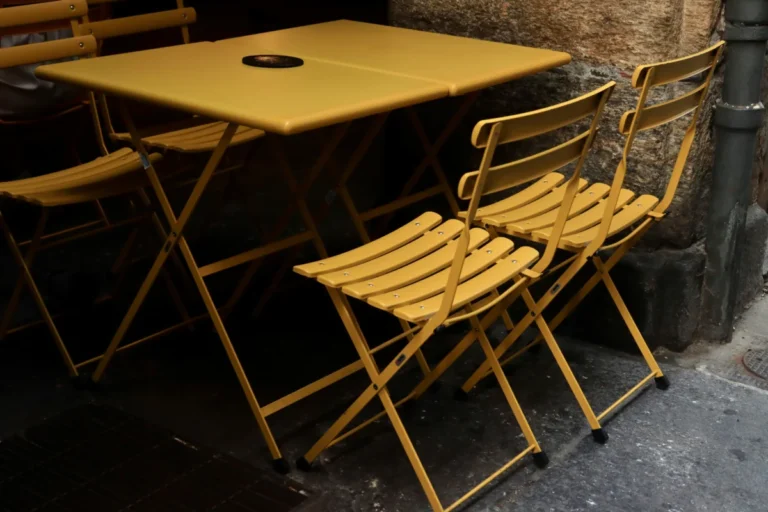 Foldable yellow bistro chairs and table on a Turin street, offering a cozy, urban ambiance.