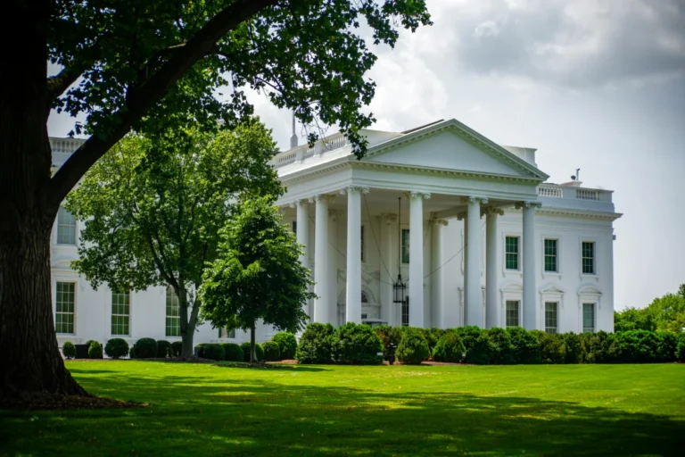 La présidente de la F.T.C. met en garde Apple contre tout parti pris dans Apple News The White House framed by trees and greenery, in Washington, D.C., under a bright sky.