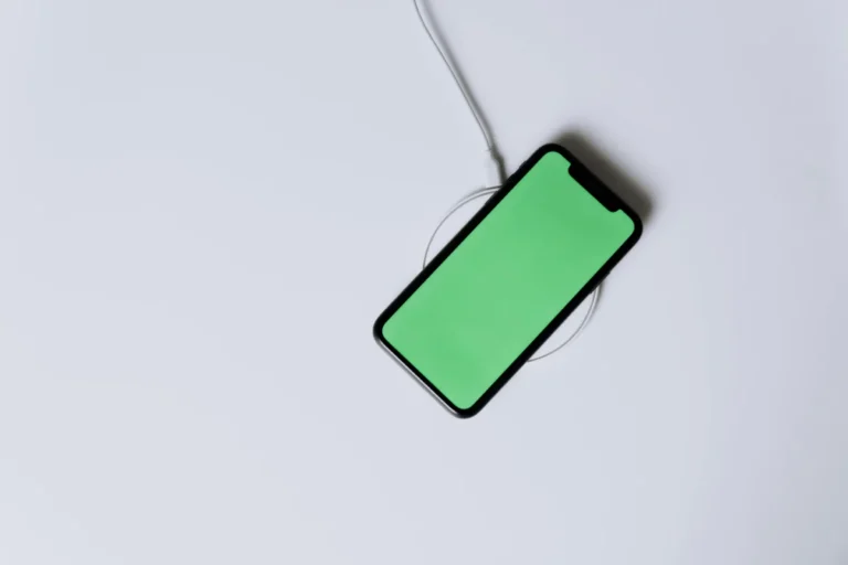 Overhead view of a smartphone with a green screen on a wireless charger, showcasing modern technology.