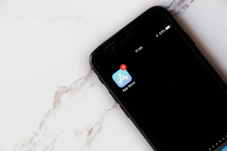 Close-up of an iPhone showing a notification on the App Store icon against a marble background.