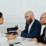Business professionals having a focused discussion in an indoor office environment with technology aid.
