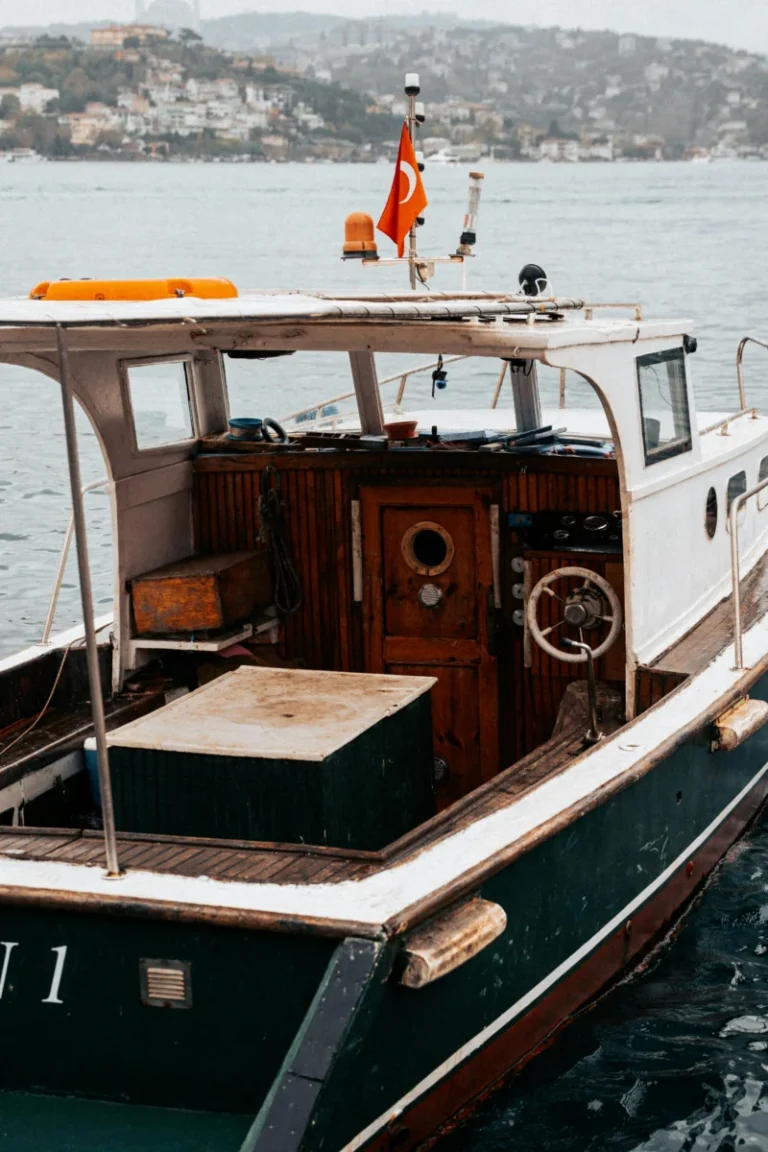 A classic wooden boat with Turkish flag on calm lake with town background.