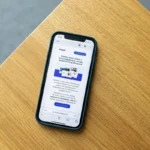 Mobile phone with an e-commerce interface on a wooden surface, illustrating online shopping technology.