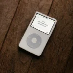Apple, le moment est venu de ressusciter l'iPod A classic white iPod with a circular touchpad placed on a wooden surface.