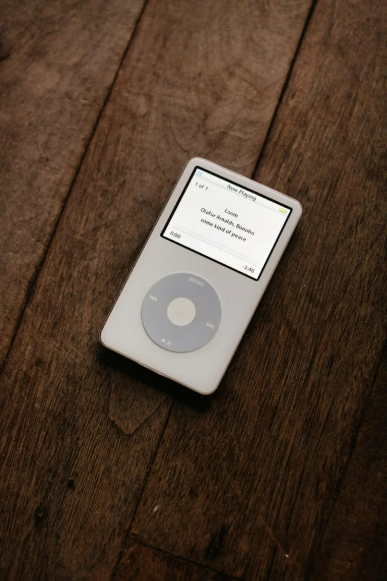 Apple, le moment est venu de ressusciter l’iPod A classic white iPod with a circular touchpad placed on a wooden surface.