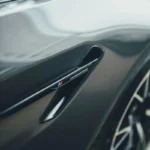 Detailed shot of BMW M5 Competition emblem on a sleek vehicle in Gurugram, India.