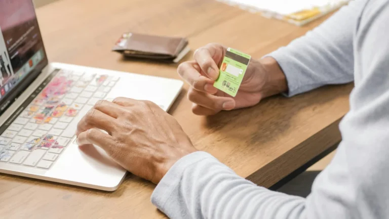 Person holds a credit card while browsing on a laptop, symbolizing convenient online shopping.