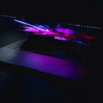 A laptop displaying a vibrant abstract design in low light, highlighting artistic and digital design concepts.