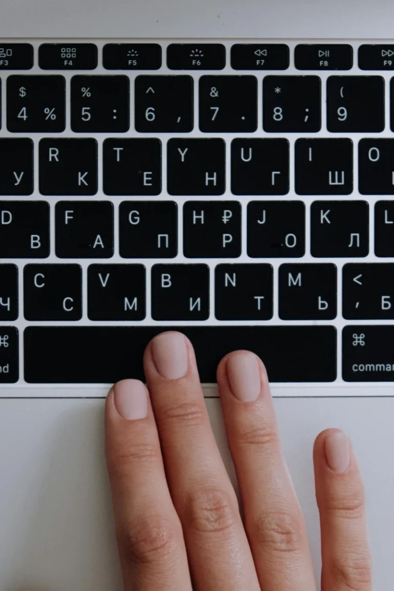 A hand typing on a laptop keyboard with Cyrillic letters, highlighting modern technology.