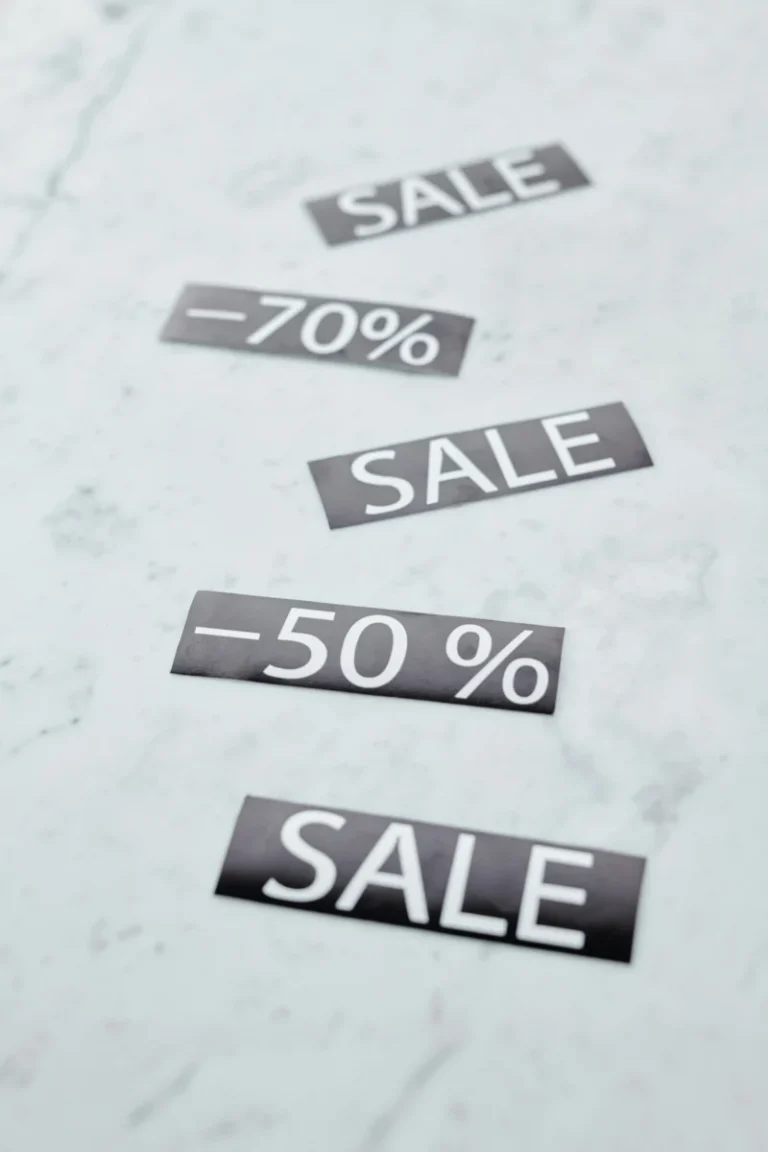 Minimalist image showing sale signs with discount percentages on a marble surface.