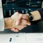 Le Samsung Smart Monitor M9 atteint un prix historique sur Amazon avec une réduction de 300 $, et découvrez d'autres offres exceptionnelles sur les moniteurs Close-up of a handshake with financial graphs on laptop screen, symbolizing a successful agreement.