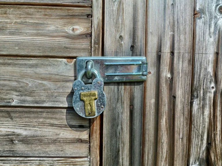 Rustic wooden door secured with a metal padlock and latch, symbolizing security and protection.