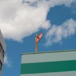 Modern building with orange satellite dish against a blue sky with clouds.