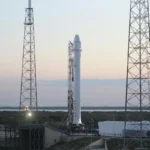 Space rocket installed on metal construction in spaceport and ready for launching against cloudless sky