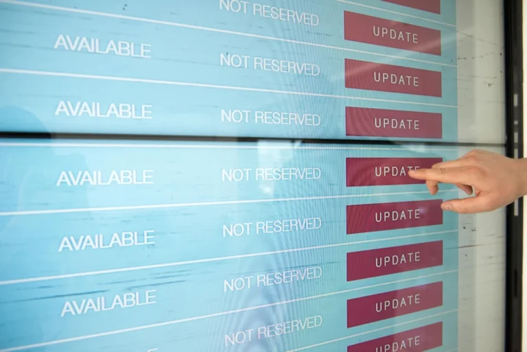 A hand interacts with a digital touchscreen interface showing availability and update options.