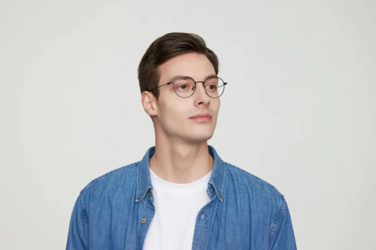 Portrait of a stylish young man in glasses wearing a denim shirt.