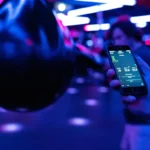 Smartphone displaying fitness tracking data next to boxing equipment under neon lighting.