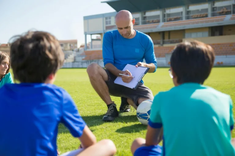 Apple TV s’associe à EverPass Media pour diffuser une programmation sportive dans les bars et hôtels Coach inspiring young players during soccer practice at a Portuguese stadium.