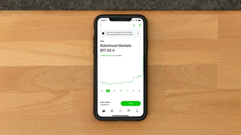 Apple et GE Aerospace en tête : cinq actions affichant des signaux d’achat prometteurs Stock trading app on smartphone displaying Robinhood Markets price on wooden desk.