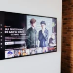 Smart TV displaying streaming content in modern living room setting with exposed brick wall.