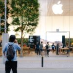 Apple ouvre son sixième Store à Pékin le 6 décembre 2025, Vision Pro en démo A busy Apple Store entrance with glass facade, trees, and people milling around.